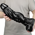 Czarne monster dildo z łuskową fakturą — wariant jasny w dłoniach